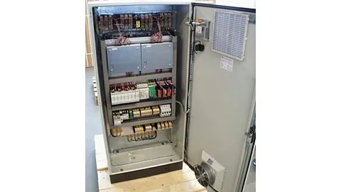 Åpent elektrisk skap med ledninger, komponenter og kjølevifte.